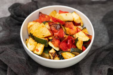 Beyaz tabakta fırında sebze. Fırında domates, kabak ve kırmızı biber. Sağlıklı vejetaryen gıda kavramı.