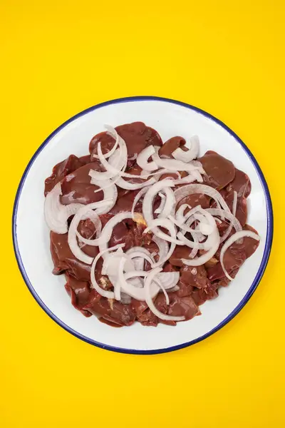 Raw chicken liver meat with onion on white big dish