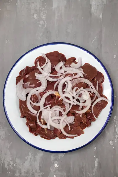 Raw chicken liver meat with onion on white big dish