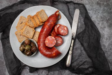 Küçük tabakta chourico ve zeytinli tost.