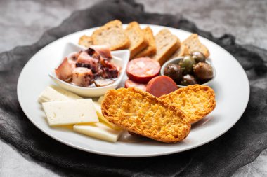 Küçük tabakta chourico ve zeytinli tost.