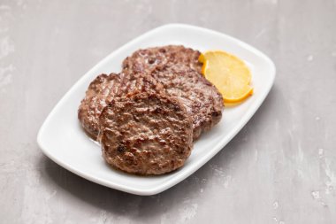 Büyük beyaz tabakta limonlu hamburger için ızgara et.