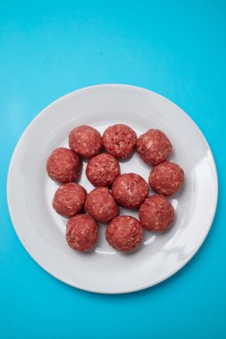 Beyaz tabakta çiğ et toplarının üst görünümü