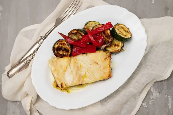 魚料理 ホワイトプレートで焼いた野菜と揚げコード魚 ロイヤリティフリーのストック画像