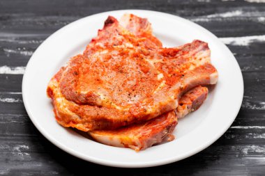 Büyük beyaz tabakta dilimlenmiş, soslu ve biberli domuz eti.