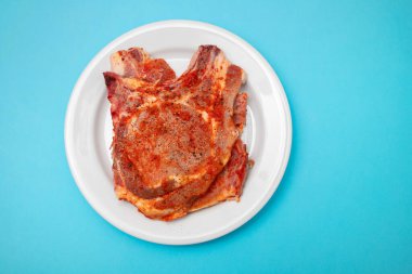 Büyük beyaz tabakta dilimlenmiş, soslu ve biberli domuz eti.