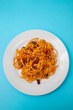 Baharatlı domates ve beyaz tabakta et karışımı erişte tai tarzı.