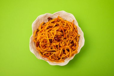 Baharatlı domatesler ve beyaz kasede et karışımı erişteler.