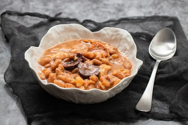 typical portuguese dish with beans and smoked sausages in white bowl