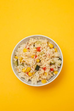 Renkli sebzelerle karıştırılmış beyaz pirinç (soğan, havuç, yeşil bezelye, mısır, yeşil fasulye) beyaz kase içinde