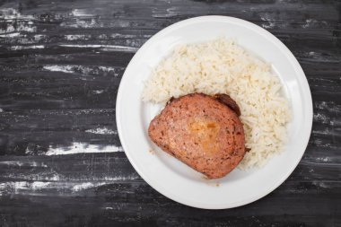 Beyaz tabakta haşlanmış pirinçli fırında köfte.