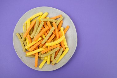 Gri tabakta otlarla pişirilmiş patates cipsi.