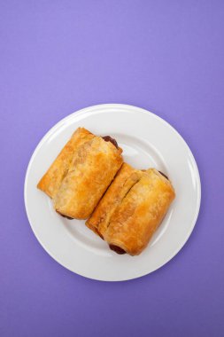 Küçük beyaz tabakta hamur içinde mini sosisler.