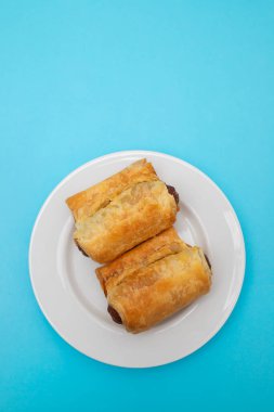 Küçük beyaz tabakta hamur içinde mini sosisler.