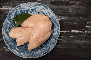 Çiğ tavuk göğsü ve büyük tabakta yaprak.