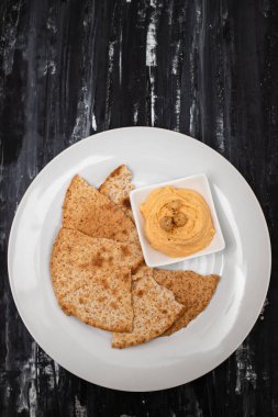 Klasik nohut humusu, zeytin yağı ve beyaz tabakta kızarmış ekmek.