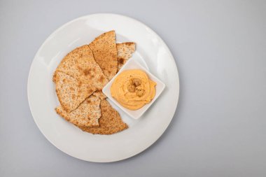 Klasik nohut humusu, zeytin yağı ve beyaz tabakta kızarmış ekmek.