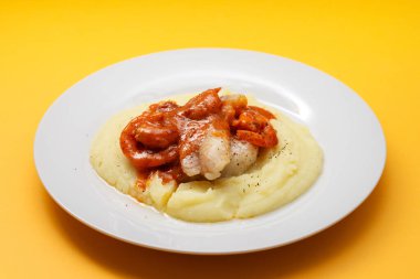 Beyaz tabakta patates püresi ve sos ile kızarmış balık.