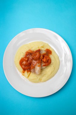 Beyaz tabakta patates püresi ve sos ile kızarmış balık.