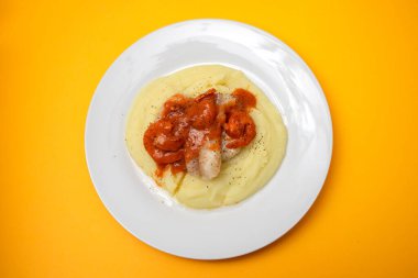 Beyaz tabakta patates püresi ve sos ile kızarmış balık.