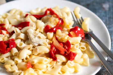 Morina balıklı makarna ve büyük beyaz tabakta kırmızı biber.