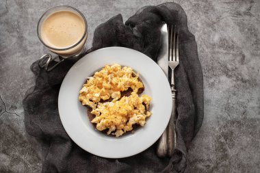 Beyaz tabakta siyah ekmekle çırpılmış yumurta.