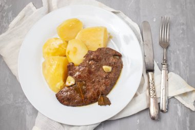 Kızarmış ciğer ve beyaz tabakta haşlanmış patates.