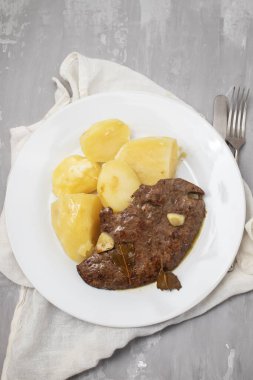 Kızarmış ciğer ve beyaz tabakta haşlanmış patates.