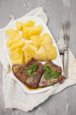 Kızarmış ciğer ve beyaz tabakta haşlanmış patates.