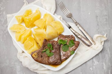 Kızarmış ciğer ve beyaz tabakta haşlanmış patates.