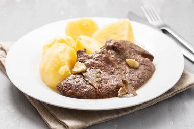 Kızarmış ciğer ve beyaz tabakta haşlanmış patates.