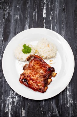 Beyaz tabakta haşlanmış pirzola ve pilav.