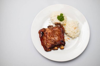 Beyaz tabakta haşlanmış pirzola ve pilav.