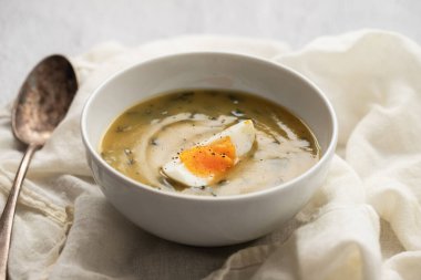 Yeşil çorba. Beyaz kasede kaynamış yumurta ile ıspanak kremalı çorba..