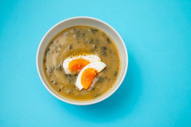 Yeşil çorba. Beyaz kasede kaynamış yumurta ile ıspanak kremalı çorba..