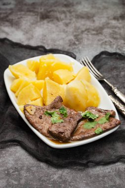 Kızarmış ciğer ve beyaz tabakta haşlanmış patates.