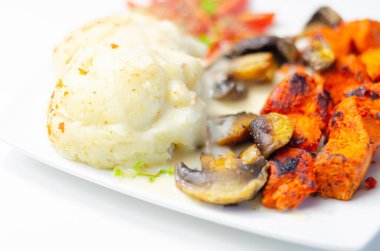 Kızarmış tavuk göğsü ve yanında patates püresi, mantar ve taze vişneli domates ve sağlıklı besinle servis edilen tatlı biberli salamura.