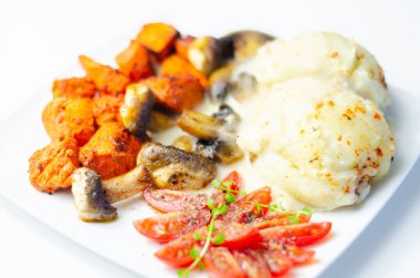 Kızarmış tavuk göğsü ve yanında patates püresi, mantar ve taze vişneli domates ve sağlıklı besinle servis edilen tatlı biberli salamura.