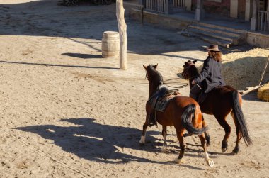 ALMERIA, SPAIN - 17 DECEMBER 2022 Dressed in distinctive Wild West costumes, actors in a Western town put on a bank robbery show clipart