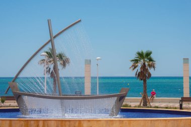 ALMERIA, İspanya - 24 Mayıs 2023 Gezinti güvertesinde büyük bir tekne çeşmesi, tekne gövdesi ve yelkeni farklı renklerde akan su perdeleridir.