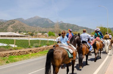 NERJA, SPAIN - 15 Mayıs 2022 Flamenko elbiseli kadınlar ve Endülüs atlarındaki erkekler en iyi geleneksel halk kostümleri ve festival töreninde yer alan geniş kenarlı şapkalar giydiler.