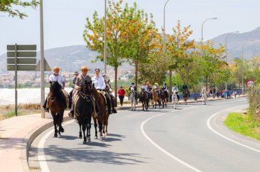 NERJA, SPAIN - 15 Mayıs 2022 Flamenko elbiseli kadınlar ve Endülüs atlarındaki erkekler en iyi geleneksel halk kostümleri ve festival töreninde yer alan geniş kenarlı şapkalar giydiler.