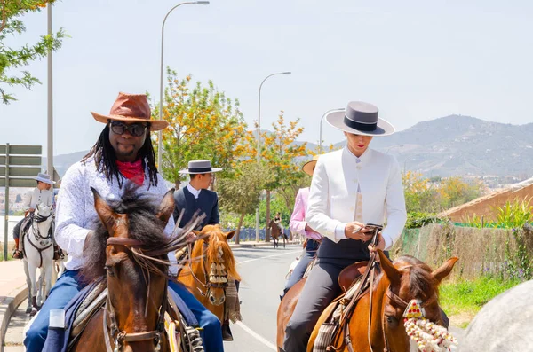 NERJA, SPAIN - 15 Mayıs 2022 Flamenko elbiseli kadınlar ve Endülüs atlarındaki erkekler en iyi geleneksel halk kostümleri ve festival töreninde yer alan geniş kenarlı şapkalar giydiler.