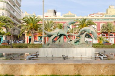 ALMERIA, İspanya - 11 Aralık 2023 Heykel, bir dikdörtgen çeşmenin ortasında yer alan ve dalgalarda oynayan beş güzel yunusu tasvir eder.