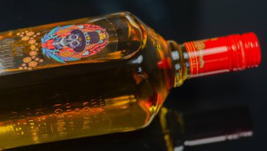 LONDON, İngiltere - 08 Mart 2024 Meksikalı sanatçı Pogo tarafından tasarlanan geleneksel bir şişe reposado tekila klasik bir kafatası motifi ile agave bitkisinden büyüyen turuncu kadife çiçekleri ile geliştirilmiş.