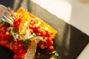 Dört peynirli ravioli domates ve fesleğen soslu siyah taş tabakta Fransa 'nın Nice şehrinden ünlü bir yemek.