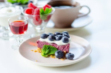 Fırında vanilya ve çilek aromalı cheesecake, sindirim bisküvisi kırıntısında yabanmersini sosu ve tatlı.