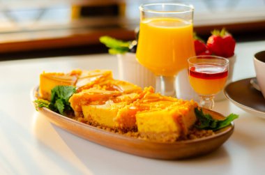 Fırınlanmış vanilya ve tropikal aromalı peynirli kek, sindirim bisküvisi kırıntısında tutku meyvesi sosu ve şekerleme.