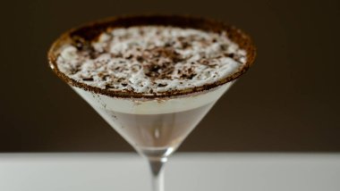 Bir martini bardağına bir çikolata martini dökülür. İçkinin üstünde çikolata garnitür var.
