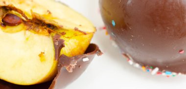 Çikolata kaplı bir elma, üzerine de şeker serpiştirilmiş. Renkli tatlılar